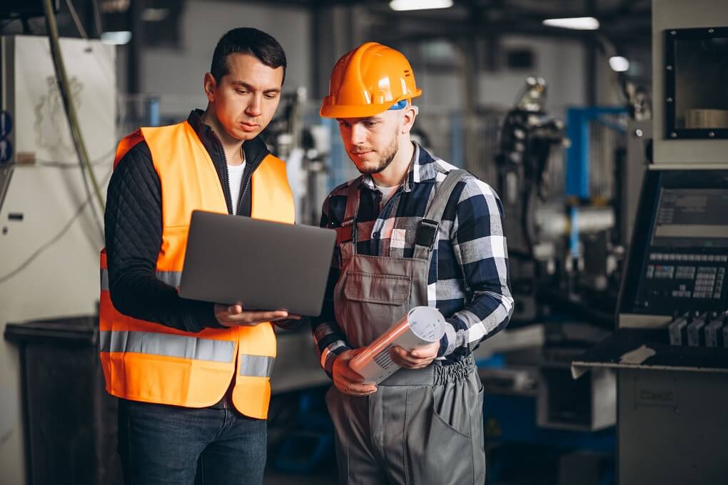 Deux travailleurs en usine examinant une tablette